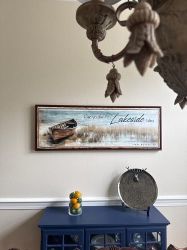 Reviewer's framed Lose Yourself in Lakeside Bliss sign hung on a wall above a blue cabinet.