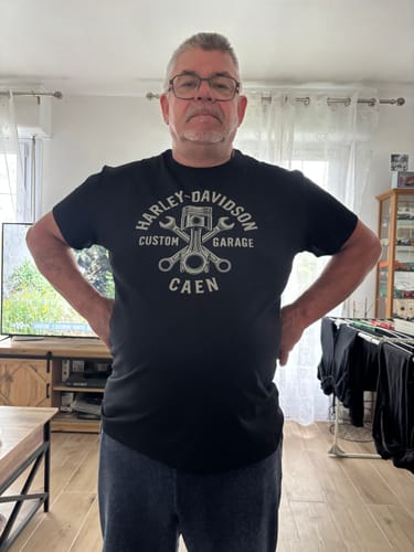 Client portant le t-shirt noir à motif graphique dans un salon.