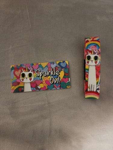 Reviewer's colorful Sparkle on Bracelet and matching card, both featuring an adorable caticorn design on a gray surface.