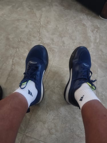 Reviewer's overhead view of their feet in navy blue Flow shoes and white socks on a tile floor.