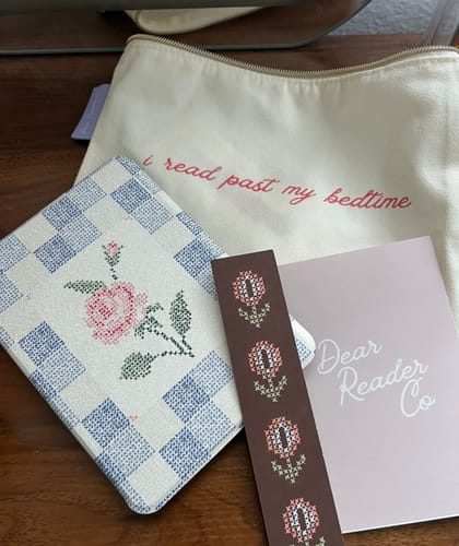Customer's Rose & Thread Kindle Case with a checkered, cross-stitch rose design, next to a pouch and bookmark.