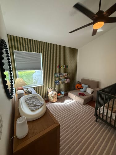 Reviewer's Tully Wallpaper with green stripes on an accent wall in a nursery.