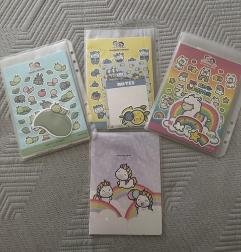 Customer's four adorable sticker packets from the Sticker Subscription, laid out on a gray textured blanket.