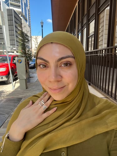Customer wearing the soft Golden Moss Premium Modal hijab outdoors on a city street.