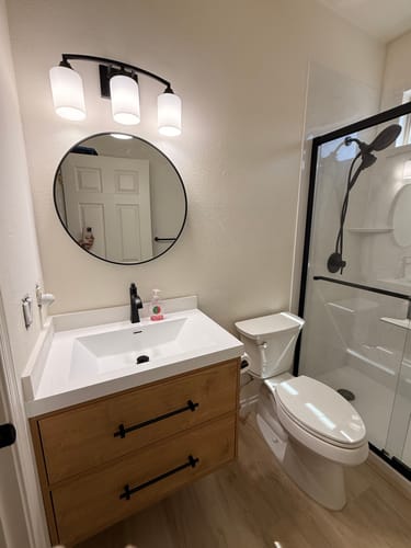 Reviewer's installed Belgian Floating Vanity with a light wood cabinet, white integrated sink, and black handles.