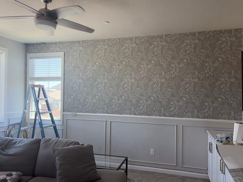 Customer's living room showing the beige Winsome Wallpaper applied as an accent wall above white wainscoting.