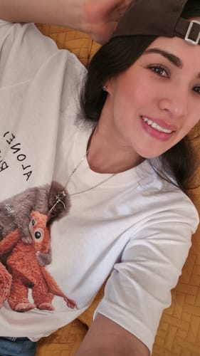 Una clienta sonriendo mientras lleva puesta la camiseta Punch blanca y está acostada.