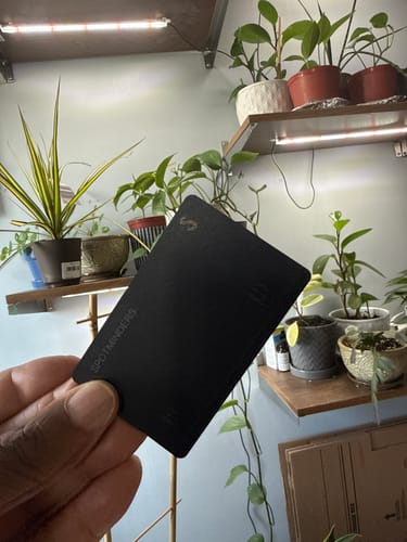 Customer holding the sleek, black SPOTMINDERS Tracking Card in their hand indoors.