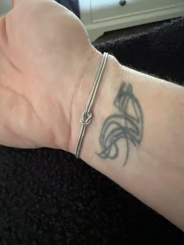 A close-up of a reviewer wearing the Forever Knot Bracelet on their wrist.