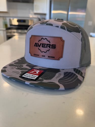 Customer's custom trucker hat with a camouflage pattern and a brown leather patch on the front.