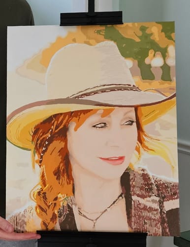 Customer's finished Custom Paint by Numbers Kit showing a portrait of a woman with red hair and a hat, sitting on an easel.