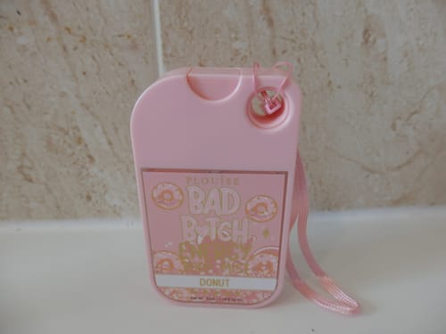 Customer's pink Bad Bitch Body Mist in the Donut scent, showing its compact, travel-friendly packaging with a wrist strap.