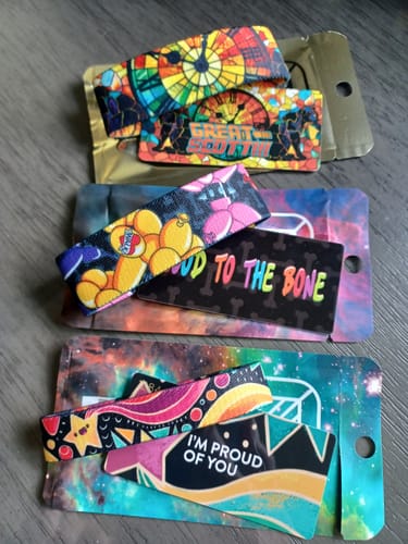 Customer's three colorful bracelets from a Mystery 3-Pack, laid out with their matching collector cards on a table.