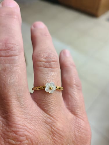 Customer showing the White Petal Shell Ring with a gold band and white flower on their finger.