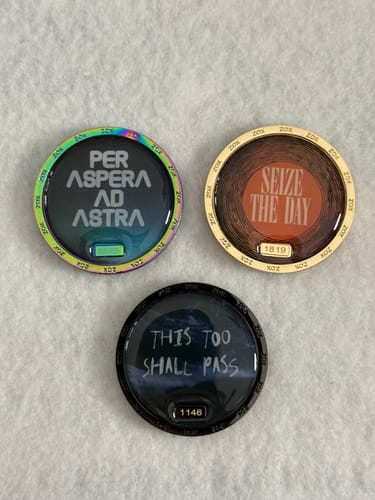 Customer's three Stoic Coin Pack coins showing the engraved text front of each.