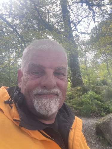 Reviewer in a close-up selfie wearing the bright yellow Ripknot™ Waterproof Anorak outdoors.