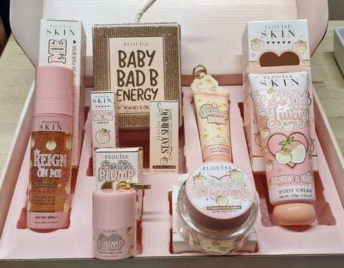 Reviewer's open Budget Box showing the 'Peaches & Dreams' skincare collection inside.