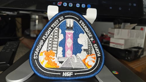 Customer's Starship Flight 12 Collectors Patch, featuring a detailed embroidered launch scene, displayed on a stand.