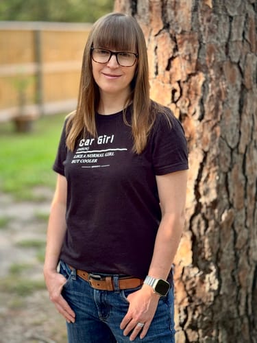 Reviewer standing outdoors wearing the black Women's Car Girl Shirt, showing its relaxed fit and printed text.