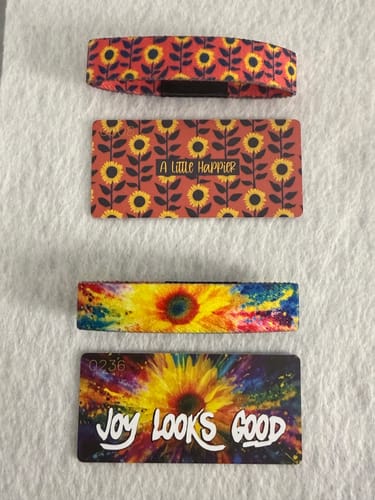 Reviewer shows two bracelets from the Sunflower Pack, 'A Little Happier' and 'Joy Looks Good,' with their matching collector cards.