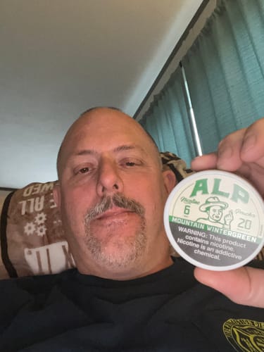 Reviewer holding a can of Mountain Wintergreen Nicotine Pouches in their hand.