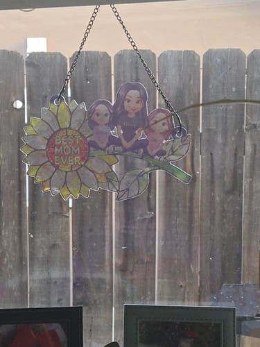 Customer's personalized sunflower suncatcher with a mom and kids design hanging in a window, appearing dull and not vibrant.