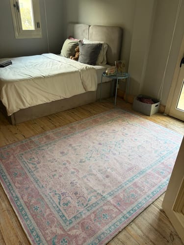 Customer's Bridgeton Faded Rug with a pink and teal design, placed in a bedroom on a wood floor.