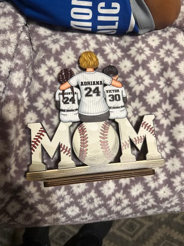 Customer's personalized wooden plaque showing a mom and two kids in baseball jerseys sitting on top of the word 'MOM'.