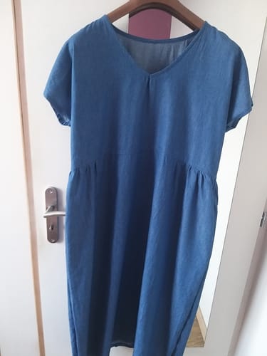 Photo d'une cliente de la robe Léna, cousue dans un tissu bleu et suspendue à un cintre.