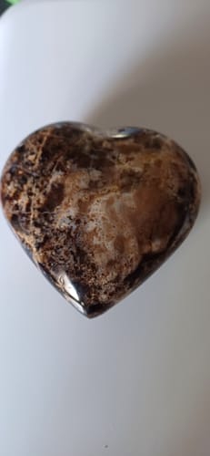 Client montrant une face de son Cœur en Opale Noire, avec des motifs beiges et marron sur une surface polie.