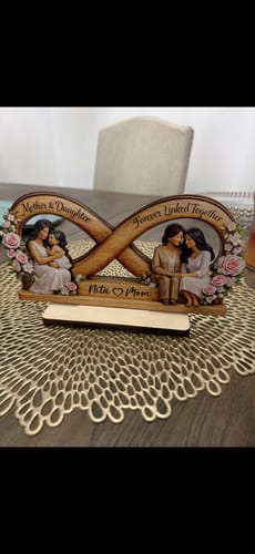 Customer's personalized wooden infinity plaque, customized with names, displayed on a decorative placemat on a table.