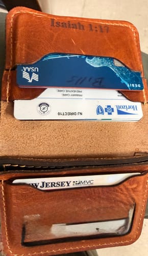 Close-up of a customer's open brown Minimalist Badge Wallet showing the filled card slots and a custom engraving.