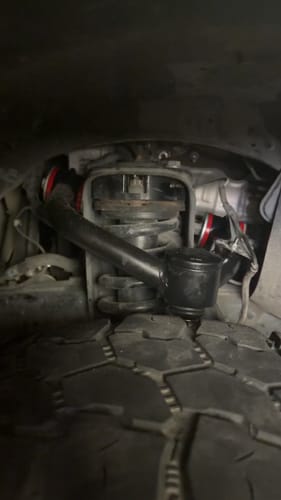 Customer's close-up view of a black Upper Control Arm with red bushings installed on their vehicle.
