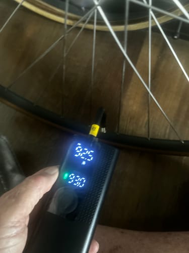 Customer holding the Airmoto connected to a bicycle tire, with the digital display reading 93.0 PSI.