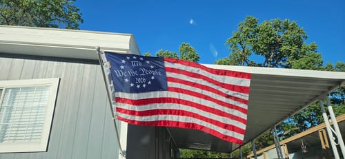 Customer's printed Betsy Ross Flag waving from a pole on the side of a house.