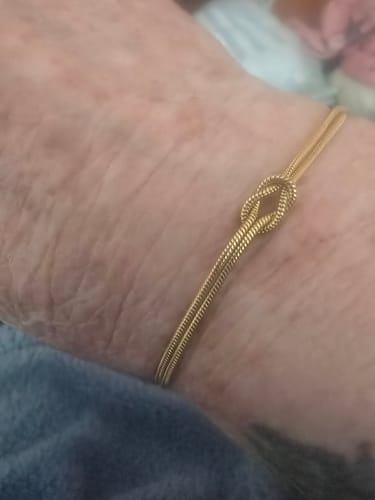Customer wearing the gold-colored Forever Knot Bracelet on their wrist.