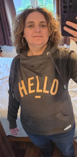 Reviewer taking a selfie while wearing the charcoal Orange Hello hoodie, showing its fit and cowl neck.