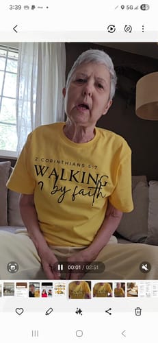 Customer wearing the yellow Walking By Faith t-shirt while sitting on a couch.