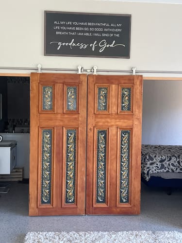 Customer's Goodness Of God Faith Sign II hanging on a wall above ornate wooden doors in their room.