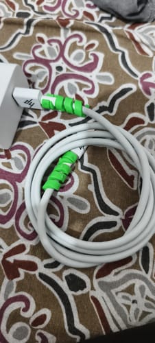 Customer's white Casence Armor charging cable coiled on a patterned surface, with green protectors on the joints.