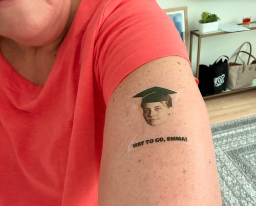 Customer's arm with a custom Graduation Hat temporary tattoo that says 'Way to Go, Emma!'