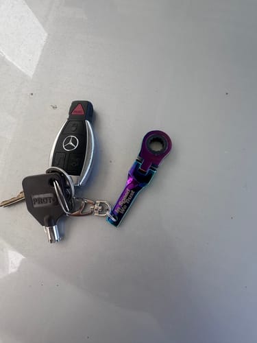 Customer's iridescent 10mm Wrench Keychain attached to their car keys on a light surface.