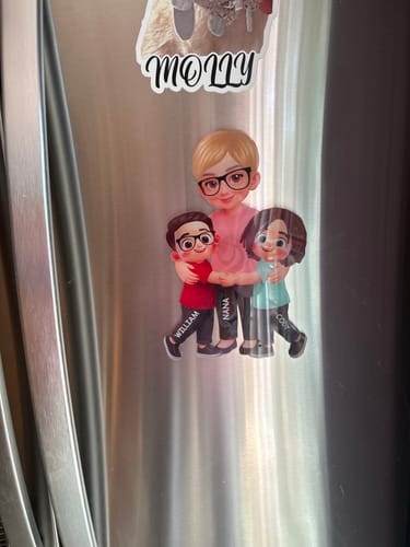 Customer's personalized acrylic magnet showing a grandma hugging two grandkids, placed on a stainless steel refrigerator.