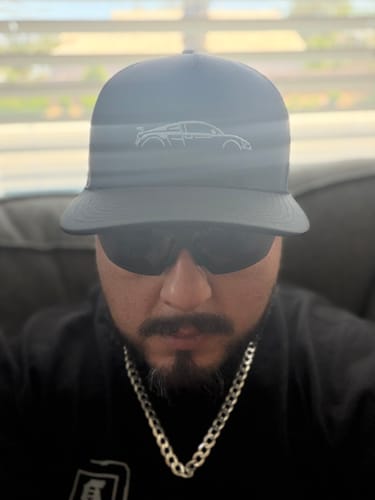 Reviewer wearing the dark DCG89 hat, showing the white car logo on the front.