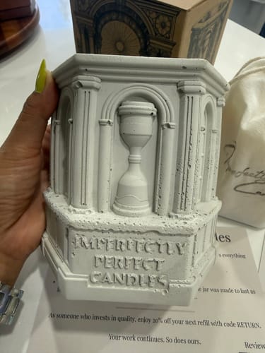 Customer holding the grey cement The Monument candle vessel, showing its ornate hourglass design.