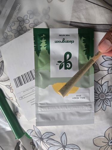 Customer holding their free gift, a single promo pre-roll, with the product packaging in the background.