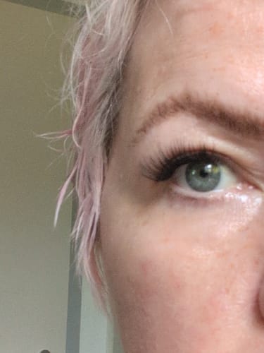 Rezensentin zeigt in einer Nahaufnahme ihr Auge mit langen Wimpern, die mit dem DIY SUPER BOND BLACK PRO angebracht wurden.