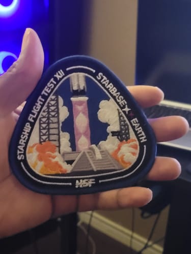 Customer's hand holding the embroidered Starship Flight 12 Collectors Patch, showing the detailed rocket launch scene.