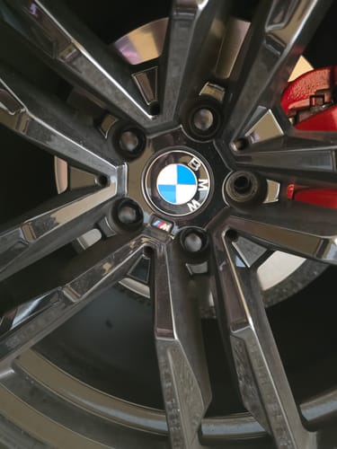 Customer's close-up of a dark BMW wheel, showing the lug bolts and one missing bolt from the installation.