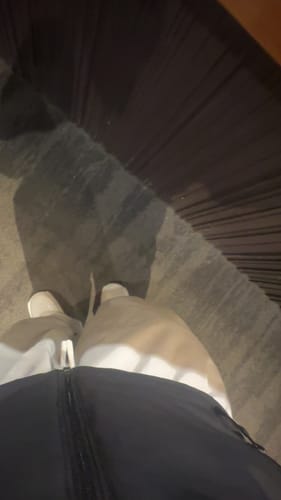 Reviewer's first-person view of the baggy black snow pants being worn indoors.